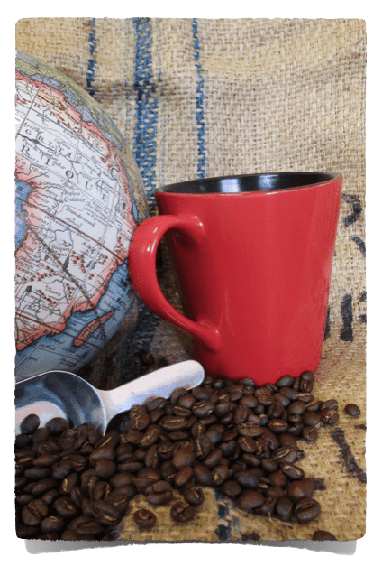 A globe, a red mug, and fresh-roasted coffee beans on burlap
